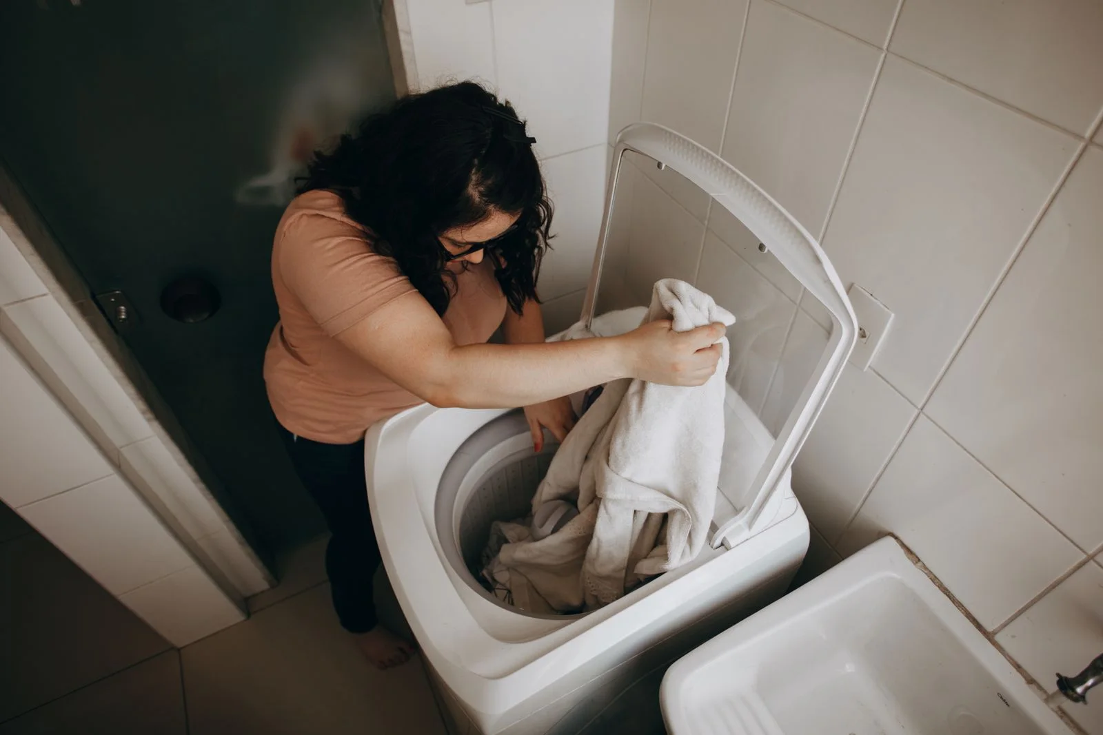 Perempuan memasukkan cucian ke mesin cuci - foto stok ilustratif, bukan staf atau lokasi Bening Laundry